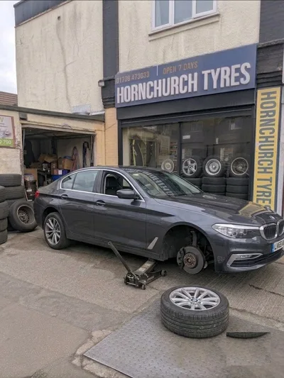 BMW 5 Series with front wheel removed for tyre fitting at Hornchurch Tyres, Hornchurch Road